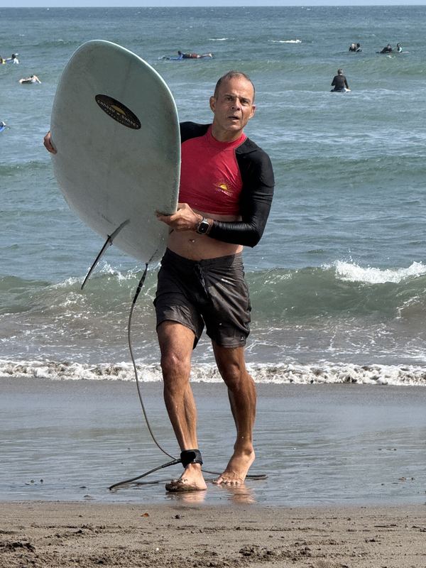 Bobby går opp av havet med surfebrettet under armen
